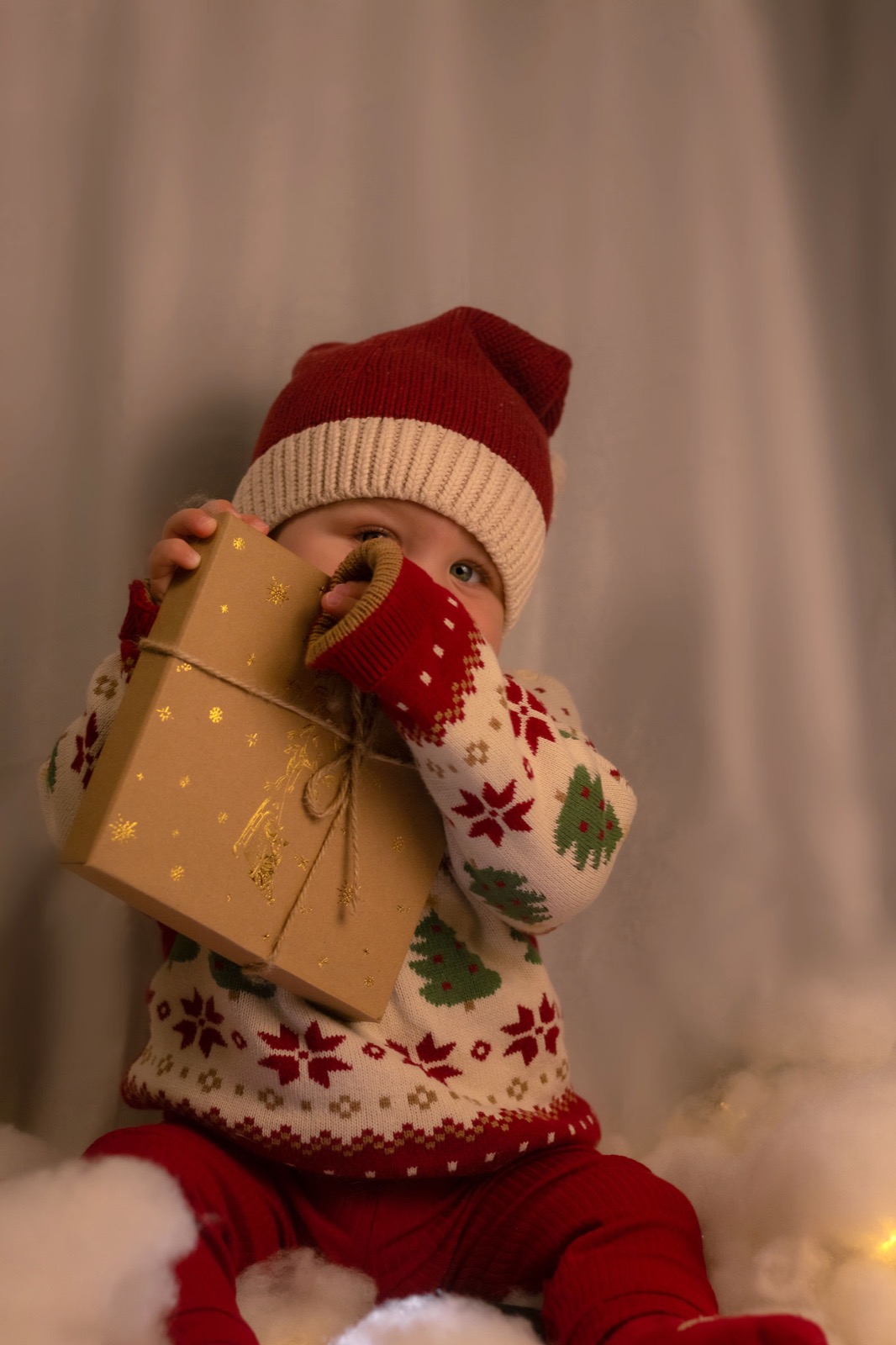 Baby in Weihnachtspullover mit einem Geschenk