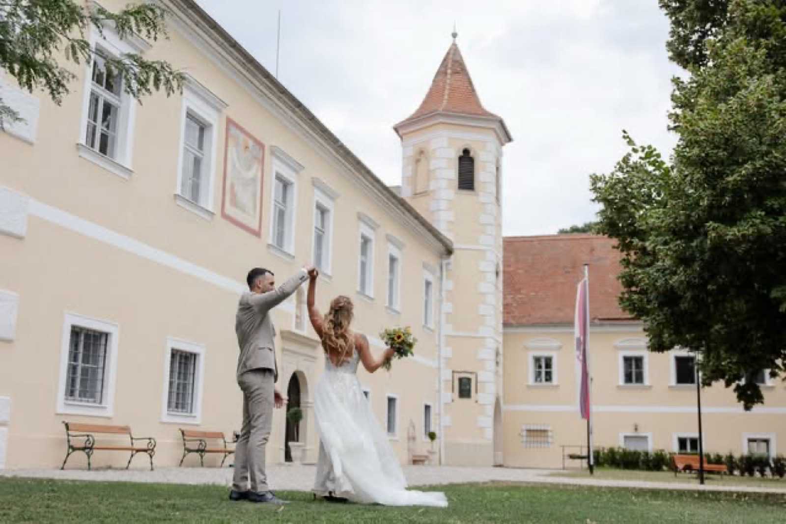 Brautpaar hält sich lachend an den Händen vor einem Schloss